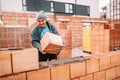 Professional worker building house walls with bricks and masonry details.