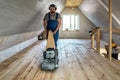 Professional worker carpenter grinding sanding a wooden floor by using floor sander. Industrial theme Royalty Free Stock Photo