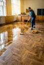 Professional worker carpenter lacquering parquet floors using roller. Parquet floor renovation Royalty Free Stock Photo