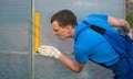 Professional worker, checks with the help of a square the correctness of the installation of the greenhouse, polycarbonate