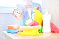 Professional worker from cleaning company holds a watch in her hand under the household chemicals. Cleaning service and time savin Royalty Free Stock Photo