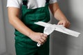 Professional worker holding putty knives with plaster indoors, closeup