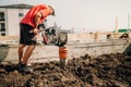 worker, industry details. Worker using vibratory compactor at house foundation