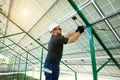 Professional worker installing solar panels on the green metal construction