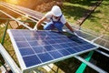 Professional worker installing solar panels on the green metal construction