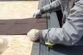 Professional worker lays asphalt tile sheet on the roof