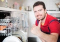 Worker repairing the dishwasher in the kitchen main focus on the hand Royalty Free Stock Photo