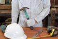 Professional worker with safety uniform holding hammer with other tools on wood workbench in carpentry workshop. Royalty Free Stock Photo