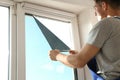 Professional worker tinting window with foil