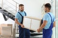 Professional workers carrying cabinet at stairs. Moving service