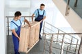 Professional workers carrying wooden rack on stairs. Moving service