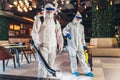 Professional workers in hazmat suits disinfecting indoor of cafe or restaurant, pandemic health risk, coronavirus