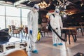 Professional workers in hazmat suits disinfecting indoor of cafe or restaurant, pandemic health risk, coronavirus