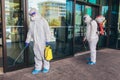 Workers in hazmat suits disinfecting outdoor of mall, pandemic health risk, coronavirus