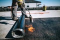 Professional workers insulating rooftop with bitumen membrane. Waterproofing details at construction site. Bituminous membrane Royalty Free Stock Photo