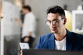 Professional young architect in glasses dressed in blue checkered jacket works on the laptop in the office Royalty Free Stock Photo