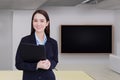 Professional young Asian business woman office worker in a black suit holds clipboard in her hands and confident smiles in office Royalty Free Stock Photo