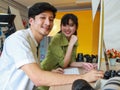 Professional young asian male and female photographers are smiling, sitting on the desk full of lens, and  camera in the modern Royalty Free Stock Photo