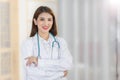 Professional young Asian woman doctor standing with arms crossed happy and smile in examination room at hospital. Wearing a white Royalty Free Stock Photo