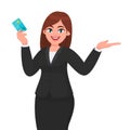 Professional young business woman showing/holding credit/debit/ATM banking card and gesturing hand to copy space side away. Royalty Free Stock Photo