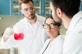 Professional young chemists wearing eyeglasses and lab coats making experiment