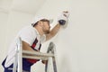 Electrician worker installs and screws, repairs surveillance video camera on wall. Royalty Free Stock Photo