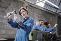 Professional young female worker with team in metalwork manufacturing factory