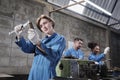 Professional young female worker with team in metalwork manufacturing factory