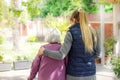 Professional young helpful caregiver walking with the elderly woman in the garden at nursing home. Elderly care concept