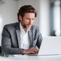 Professional Young Man in a Tailored Suit, Working Diligently on a Laptop in a Modern Office Environment During Daytime, Royalty Free Stock Photo