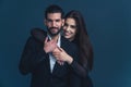 Professionally dressed beautiful dark-haired couple hugging agains dark background. Medium studio copy space shot. Young