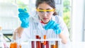 Professor woman researcher white gown prepares testing chemical liquid with science equipments on desk. with face concentration. W Royalty Free Stock Photo