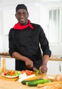 Proffesional male cook in black uniform chopping vegetables