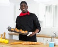 Proffesional man in black chef uniform holding sheet pan with just baked cupcakes