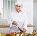 Proffesional woman cook in white uniform chopping vegetables