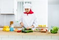 Proffesional woman cook in white uniform chopping vegetables