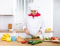 Proffesional woman cook in white uniform chopping vegetables