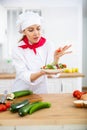 Proffesional woman cook in white uniform chopping vegetables