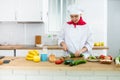 Proffesional woman cook in white uniform chopping vegetables