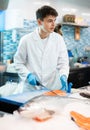 Proficient salesman cutting fish fillet in fish store