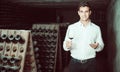 Proficient smiling man holding glass of wine in cellar