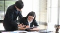 Proficient young male employee explaining a business analysis to his female colleague in office.