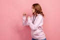 Profile of aggressive teenager girl in hoodie standing with clenched fists and furiously looking left, ready to fight Royalty Free Stock Photo
