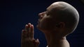 Profile bald woman folded hands in prayer. dark background Royalty Free Stock Photo