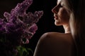 profile of a beautiful blonde woman with a bare shoulder and a bouquet of lilacs