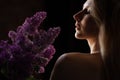 profile of a beautiful blonde woman with a bare shoulder and a bouquet of lilacs