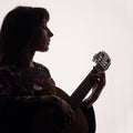 Profile of a beautiful girl playing the guitar. Silhouette. Copy space. A square picture. Royalty Free Stock Photo