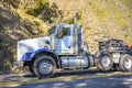 Profile of big rig powerful day cab semi truck with oversize load sign on the roof transporting oversized cargo on step down semi Royalty Free Stock Photo