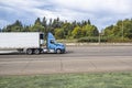 Profile of the blue day cab big rig semi truck transporting frozen cargo in reefer semi trailer driving on the wide highway road Royalty Free Stock Photo
