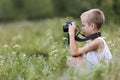 Profile close-up portrait of young blond cute handsome child boy with camera taking pictures outdoors on bright sunny spring or Royalty Free Stock Photo